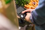 Mann verdeckt PIN-Pad bei Eingabe im Supermarkt